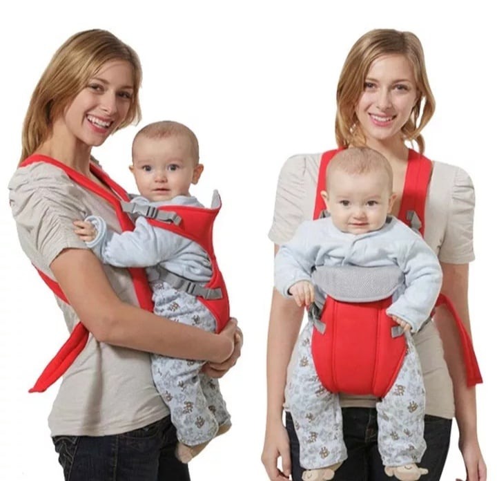 Red adjustable baby carrier with safety belt, toddler facing front on caregiver