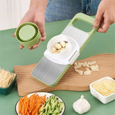 Green manual food grater with stainless grating surface and veggie holder, in use